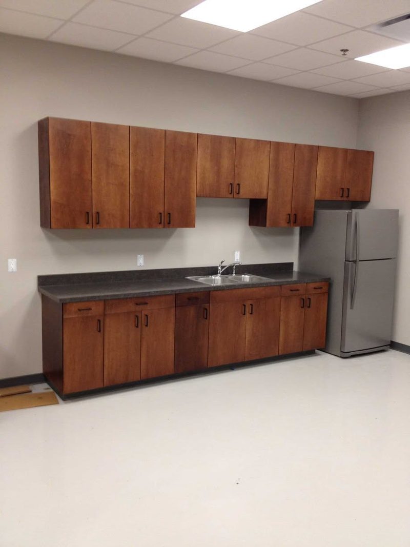 Break room with wood-look laminate base and wall cabinets, a laminate countertop and a stainless sink