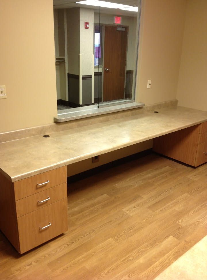 Reception workstation with laminate drawer pedestals and a long laminate work surface at an interior window
